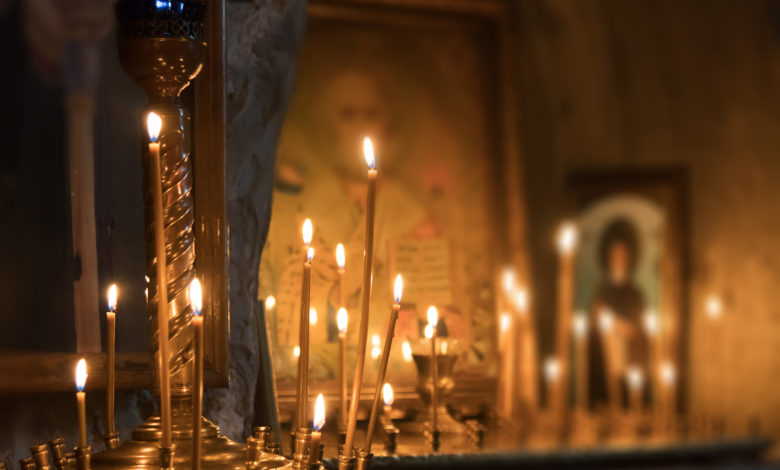 църква със запалени свещи пред иконата